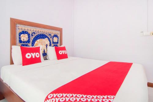 a bed with red and white pillows on it at Baan Taklom Chomtalay in Cha Am