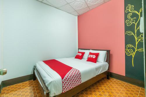 Un dormitorio con una cama con dos almohadas rojas. en OYO 608 Maleena Home, en Krabi