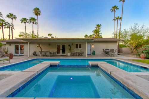 a swimming pool in front of a house with palm trees at Vintage Paseo Getaway in Palm Desert