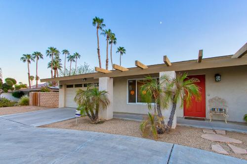 a house with a red door and palm trees at Vintage Paseo Getaway in Palm Desert