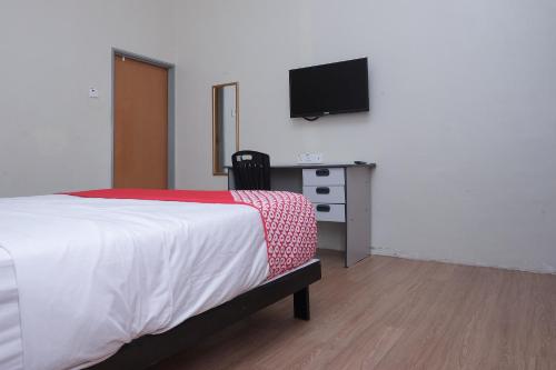 a bedroom with a bed and a desk with a television at Hotel O Kay Inn Kerteh in Kertih