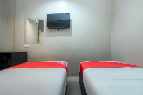 two beds in a room with a tv on the wall at Hotel O Nice Stay Three Six Five Services in Sibu