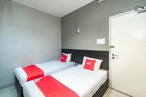 two beds in a small room with red pillows at Hotel O Nice Stay Three Six Five Services in Sibu