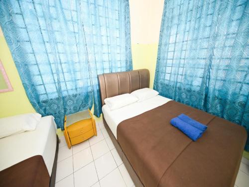 a bedroom with two beds and a blue curtain at Hotel O Iman Roomstay Gua Musang in Gua Musang