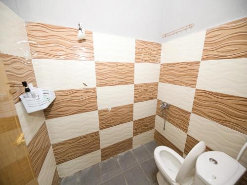 a bathroom with a toilet and a checkerboard wall at Hotel O Iman Roomstay Gua Musang in Gua Musang