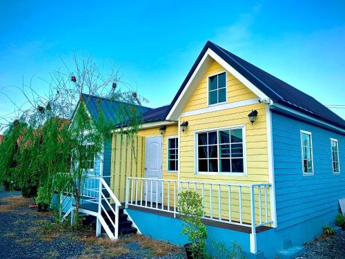 une petite maison jaune et bleue avec une terrasse couverte dans l'établissement Chai Na Resort, à Bangkok