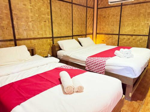 a room with three beds with red and white sheets at Honeyland Resort in Chiang Mai