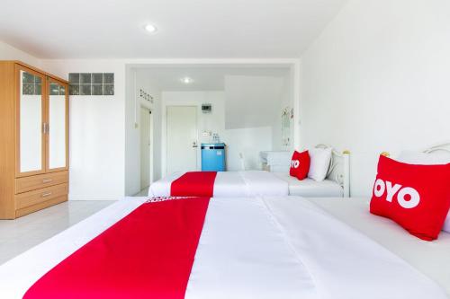 two white beds with red pillows in a room at Sabai Place in Hua Hin