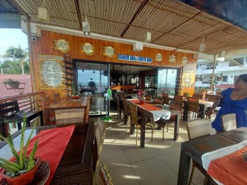 a restaurant with tables and chairs and a woman standing in front at OYO 1130 Thrivers Hometel in Puerto Galera