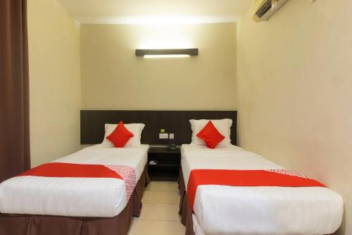 two beds in a hotel room with red pillows at Hotel O Bei King in Sitiawan
