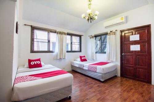 a bedroom with two beds with red pillows at Piyapruk Resort in Nakhon Ratchasima