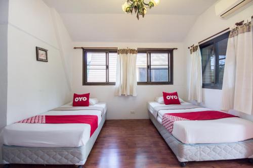 two beds in a room with two windows at Piyapruk Resort in Nakhon Ratchasima