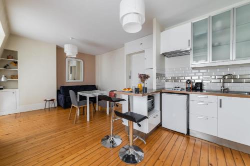 une cuisine avec des armoires blanches et une table avec des chaises dans l'établissement Studio cosy proche Opera Bastille paris 11, à Paris