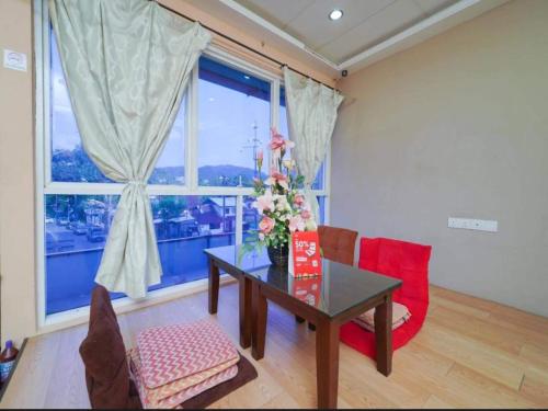 a living room with a table and chairs and a window at Hotel O J Stay Guesthouse in Jelutong