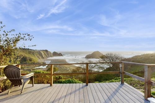 a chair sitting on a deck looking at the ocean at Greenwood Beach Cottage in Elk