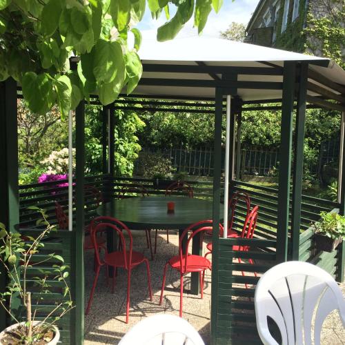 a gazebo with a table and red chairs at Pension Hönel-Hof Bad Schandau in Bad Schandau
