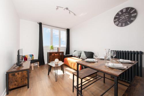 - un salon avec une table et une horloge murale dans l'établissement L Horizon Saint Cyprien, à Toulouse