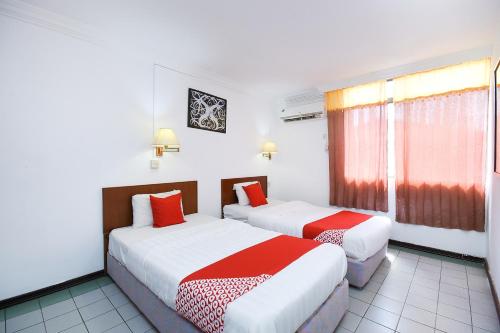 two beds in a hotel room with red and white sheets at Super OYO 1018 Telang Usan Hotel Miri in Miri
