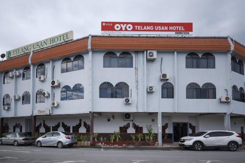 a white building with cars parked in front of it at Super OYO 1018 Telang Usan Hotel Miri in Miri