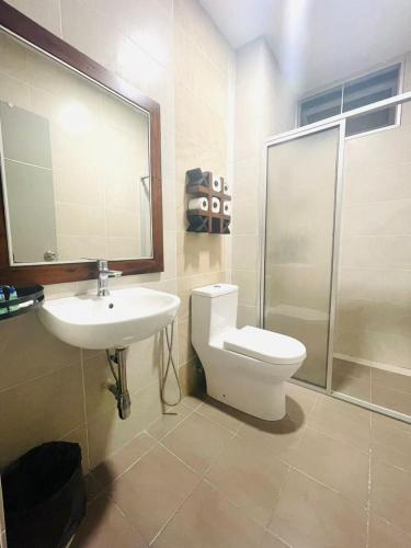 a bathroom with a toilet and a sink and a shower at Hotel O Hi-homestay in Sibu