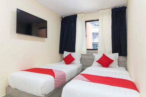 two beds in a room with a flat screen tv at Hotel O Kl Centre Point in Kuala Lumpur