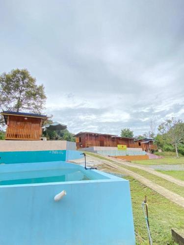 a blue swimming pool with a train in the background at Hotel O Disan Baang Kiulu in Kiulu