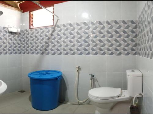 a bathroom with a toilet and a blue trash can at Hotel O Sri Ayu Inn in Kampung Gurun