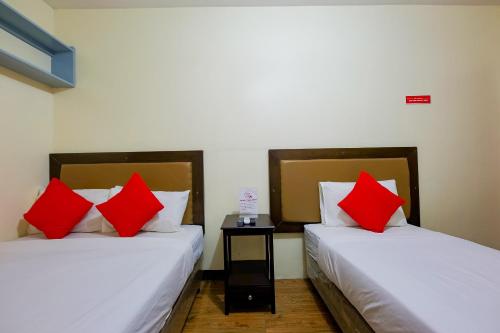 two beds with red pillows in a room at OYO 431 Apollo 11 Apartelle in Manila