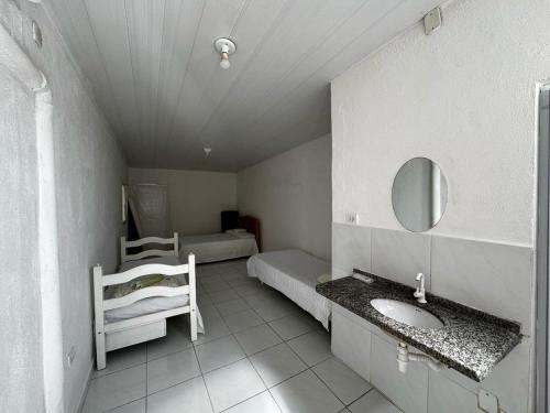 ein Badezimmer mit Waschbecken, Bett und Spiegel in der Unterkunft Chalé Casa da Barra in Barra de São Miguel