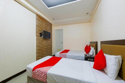 two beds in a hotel room with red pillows at OYO 431 Apollo 11 Apartelle in Manila