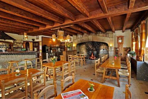 un restaurant avec des tables et des chaises en bois et une cheminée dans l'établissement Le Relais de l'Aubrac, à Nasbinals