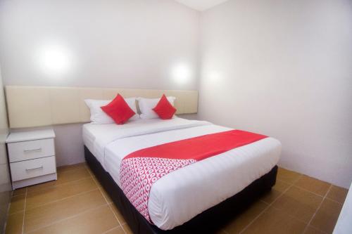 a bedroom with a large bed with red pillows at Hotel O iBC36 Business Stay in Kuching