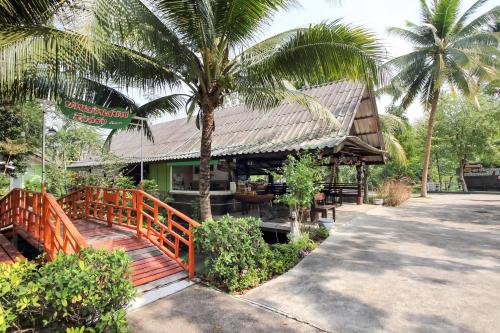a restaurant with a wooden bridge and a palm tree at OYO 606 Baan Suansabai Pleanpanmai Resort Amphawa in Samut Songkhram