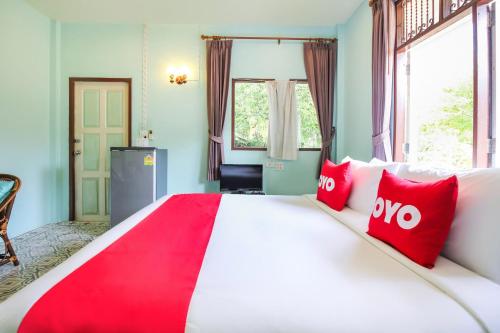 a bedroom with a large bed with red pillows at OYO 606 Baan Suansabai Pleanpanmai Resort Amphawa in Samut Songkhram