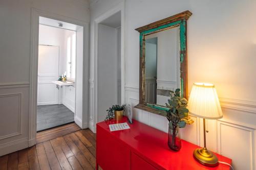 une commode rouge avec un miroir et une lampe dessus dans l'établissement Apt 4 guests Place des Victoires, à Paris