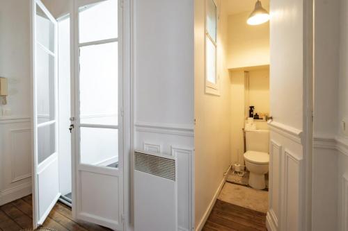 une salle de bain blanche avec toilettes et fenêtre dans l'établissement Apt 4 guests Place des Victoires, à Paris