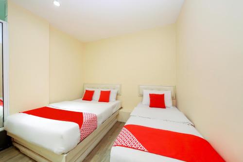 two beds in a room with red and white sheets at OYO 479 The Green Hotel in Ampang