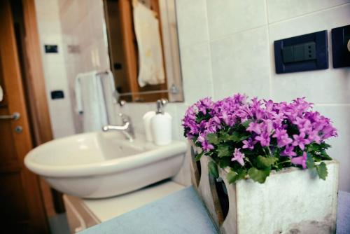 a bathroom with a sink and a vase of purple flowers at La casa di via Argine in Pozzonovo