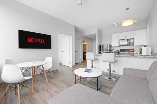 a living room with a couch and tables and a kitchen at Luxe Condo in Downtown Cleveland l 2 TV's l Parking in Cleveland