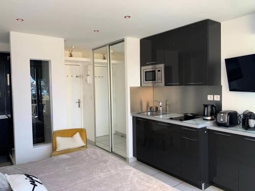 une cuisine avec des armoires noires et un four micro-ondes dans l'établissement Résidence Port Nature Colline 5 - Studio 2 personnes Port Nature Colline 5 MAE-5291, au Cap d'Agde