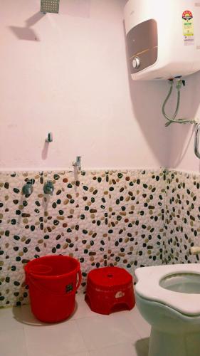 a bathroom with a toilet and red buckets in it at Vardaan Rooms in Prayagraj