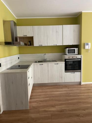 a kitchen with white cabinets and a stove top oven at Terrazza sul Parco in Comano Terme