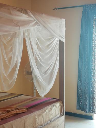a bed with a white canopy and a blue curtain at Maison Manour chambre 'soft breeze' in Mbour