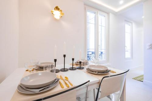 une salle à manger blanche avec une table et des chaises blanches dans l'établissement Haussmann Apartment - Champs-Élysées, à Paris
