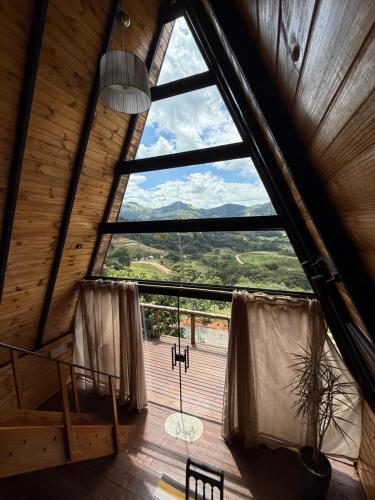 a large window in a room with a view at Chalé Canto da Mata - Com Piscina e Café da Manhã in Sapucaí-Mirim