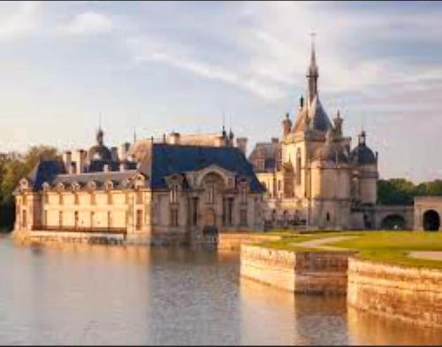 a large castle sitting on top of a body of water at Superbe appartement terrasse Chantilly Bois saint Denis in Gouvieux