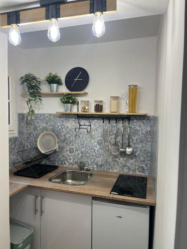 une cuisine avec un évier et une horloge murale dans l'établissement La maison des remparts, à Bergerac