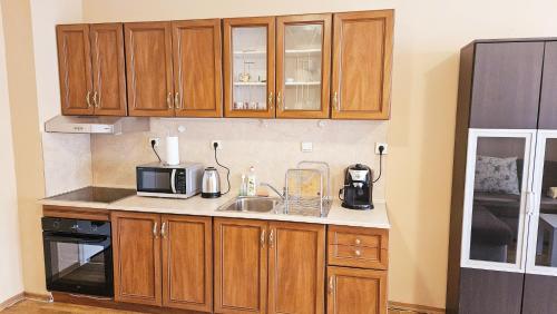 a kitchen with wooden cabinets and a sink and a microwave at Green House Apartment in Burgas City
