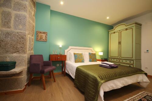 a bedroom with a bed and a chair at Paço de Vilharigues in Vouzela