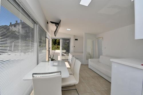 Una sala de estar con una mesa y sillas blancas. en Apartments Lux with pool, en Matulji